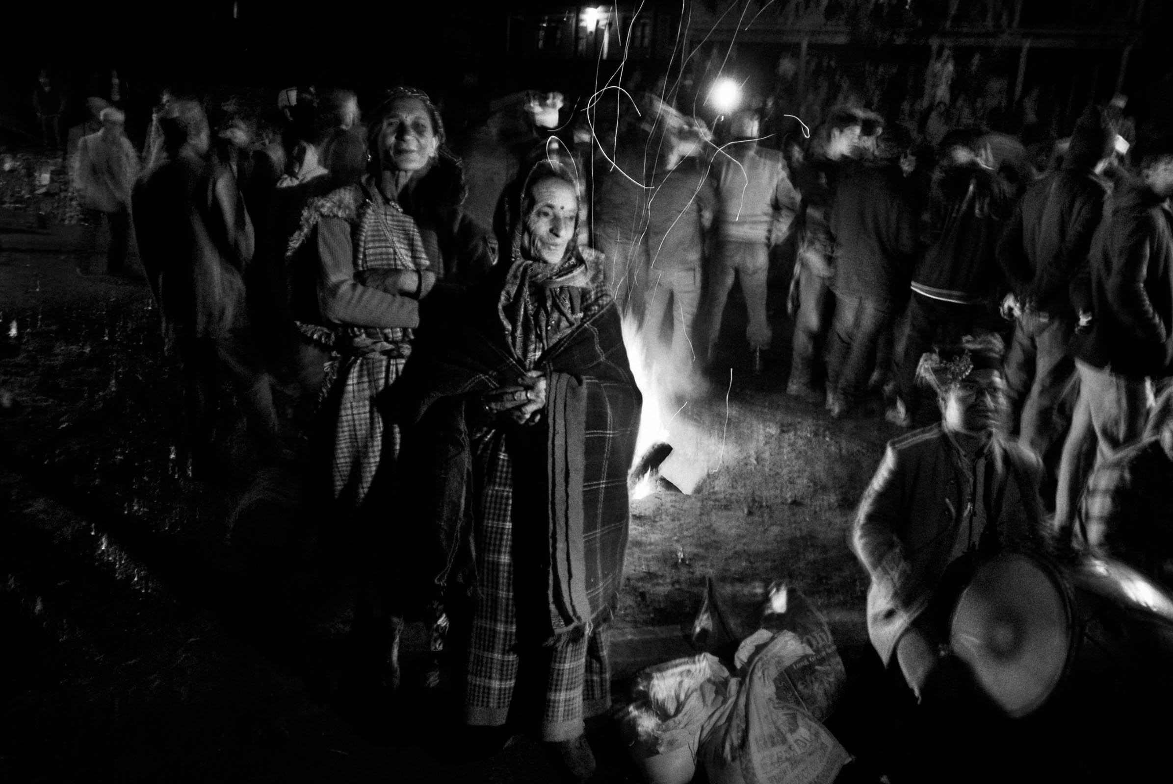 Menschen in traditionellen Gewändern um ein Lagerfeuer bei Nacht