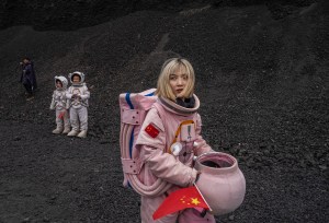 A person walks the surface of a planet with a China flag